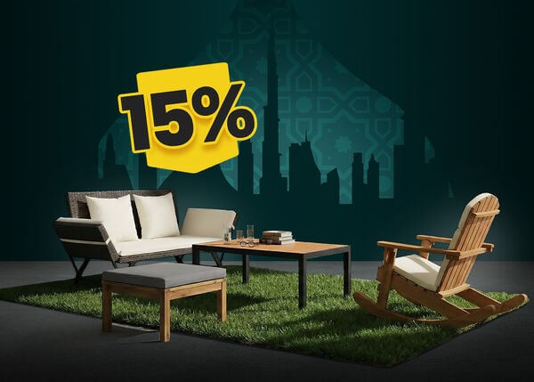 Outdoor sofa with white cushions, a wooden rocking chair, ottoman, and coffee table on a green rug, with a city skyline backdrop and a yellow 15% discount tag.