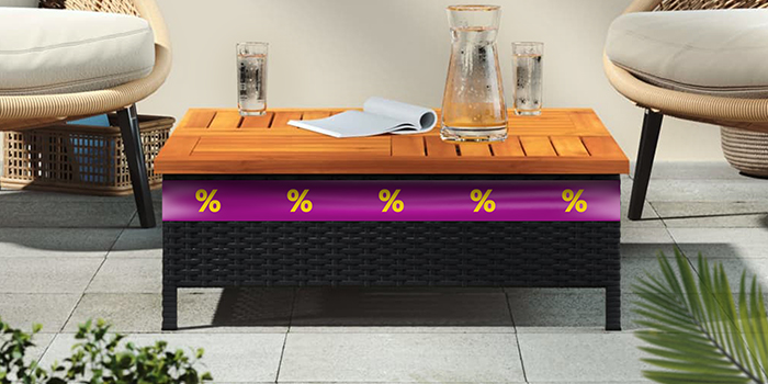 Black rattan and wooden slatted coffee table, placed between two chairs on an outdoor patio, with a purple promotional band featuring yellow discount icons. Click to shop the collection.
